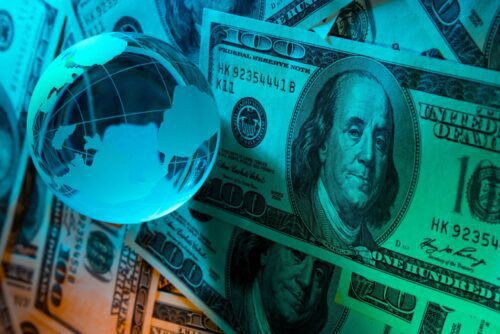 variação do dólar: imagem do globo terrestre mais, notas de dólar na cor azul-água.