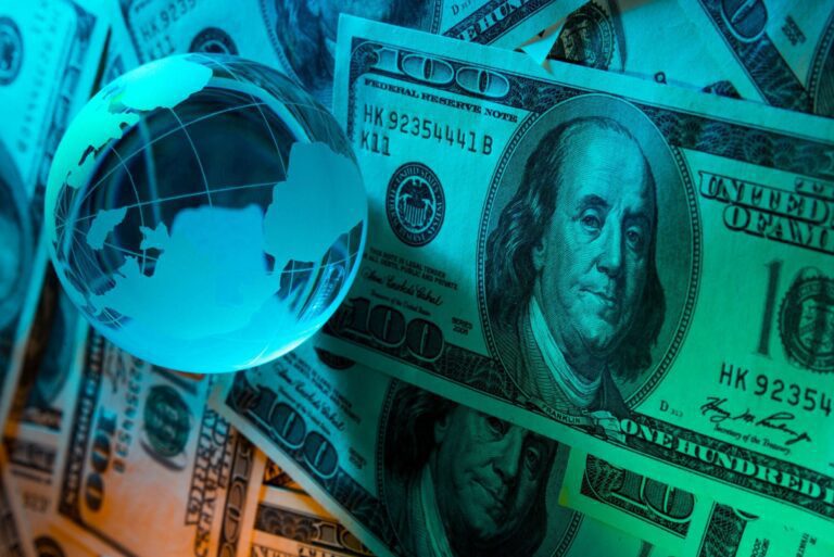 variação do dólar: imagem do globo terrestre mais, notas de dólar na cor azul-água.