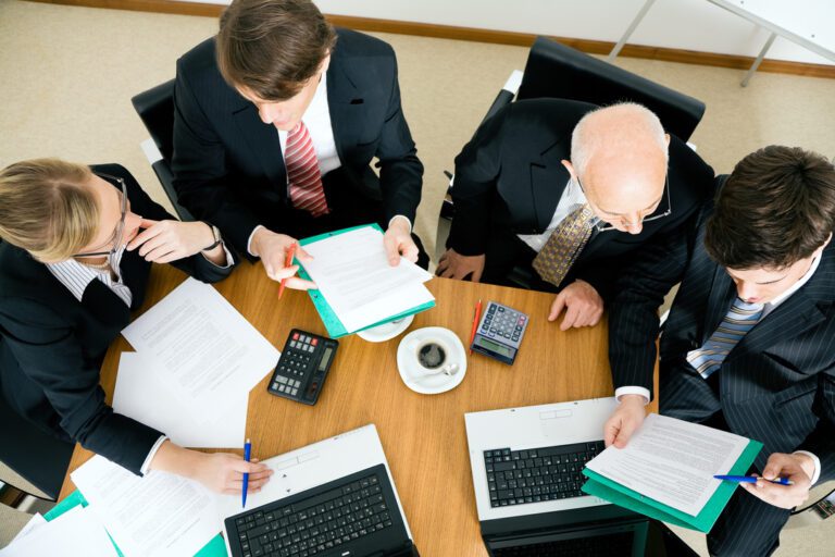 Quatro pessoas de terno analisam informações em uma reunião do Copom, o Comitê de Política Monetária