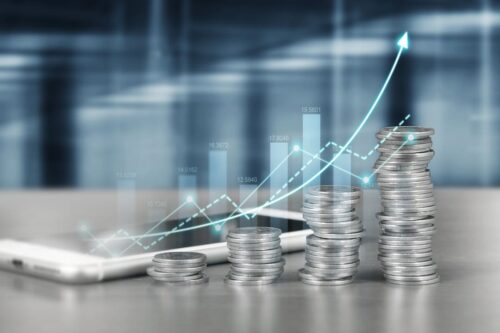 Juros Sobre Capital Próprio: pilhas de moedas na cor prata em sequência e com gráficos.