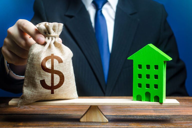 BBFI11B: uma balança com um saco de dinheiro numa ponta e na olha um prédio verde de brinquedo.