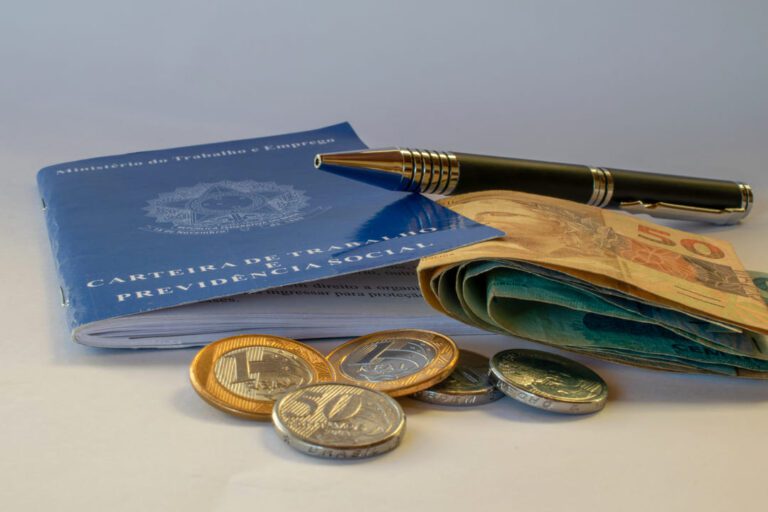 inss: uma carteira de trabalho, uma caneta, duas moedas de um real e três de 50 centavos e algumas notas de dinheiro.