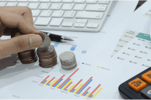 tesouro direto: gráfico de bar nas cores vermelha, azul e amarela. Pilhas de moedas ao lado, uma caneta preta com cinza.