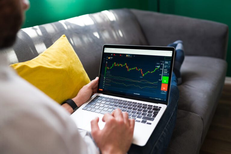tradingview: uma pessoa sentada no sofá com notebook no colo analisando as oscilações do mercado financeiro.