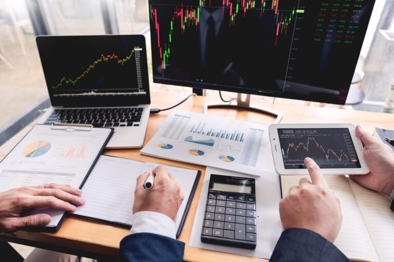 Índices de rentabilidade: uma mesa com computador e na tela tem alguns gráficos mostrando as oscilações do mercado financeiro.