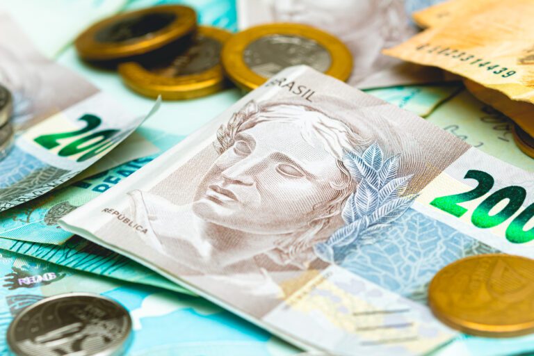 NTN-B: notas de 200 reais e algumas moedas de um real e cinquenta centavos espalhadas.