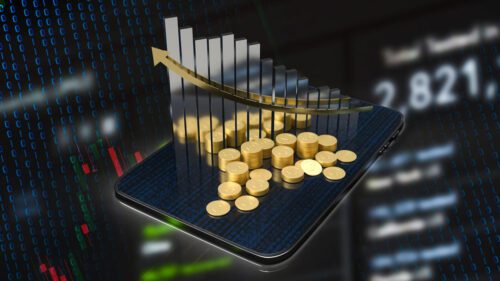 Tablet com moedas de ouro empilhadas sobre o dispositivo, ao fundo gráfico de investimentos representando o Ibovespa Smart Dividendos.