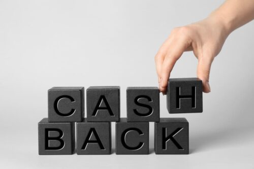 Mão empilhando cubos pretos com letras gravadas que formam a palavra cashback.