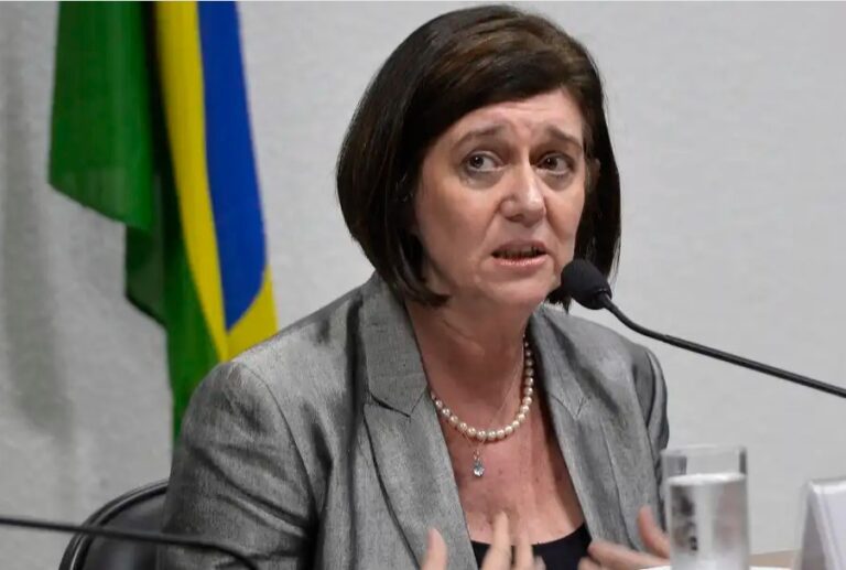 Nova CEO da Petrobras falando em um microfone com bandeira do Brasil atrás