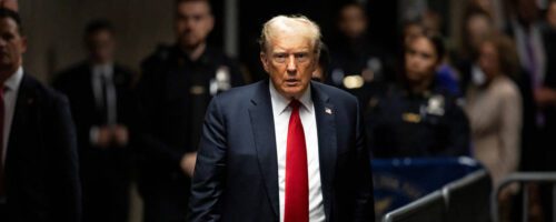 Trump de terno e gravata na frente de um monte de gente