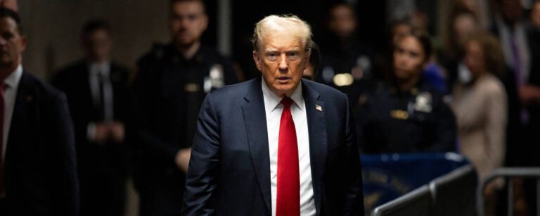 Trump de terno e gravata na frente de um monte de gente