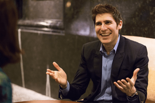 Eduardo Saverin, cofundador do facebook, sorri com braços abertos durante entrevista.