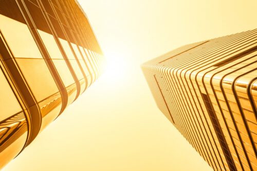 Dois prédios visto de baixo com céu ensolarado