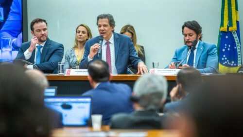 Fernando Haddad de terno e gravata falando em um microfone