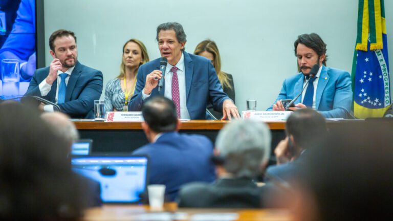 Fernando Haddad de terno e gravata falando em um microfone