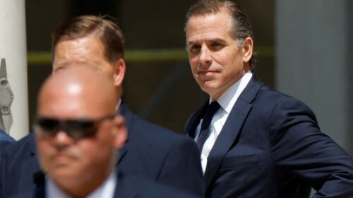 Hunter Biden de terno e gravata sendo escoltado por seguranças
