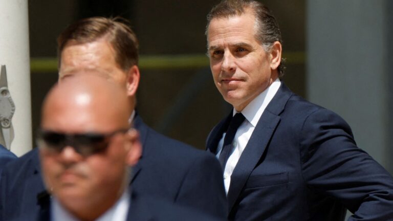 Hunter Biden de terno e gravata sendo escoltado por seguranças