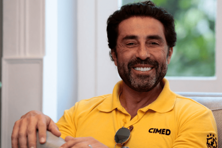 CEO e presidente da Cimed, João Adibe, sorri para foto com a camisa de sua empresa.
