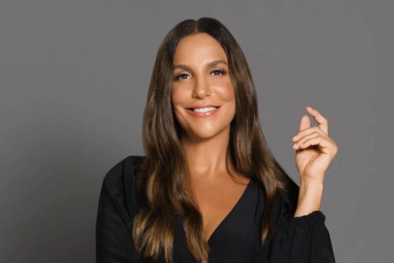 Artista Ivete Sangalo sorridente com cabelo longo e castanho, vestindo preto, destacando a fortuna da Ivete Sangalo.