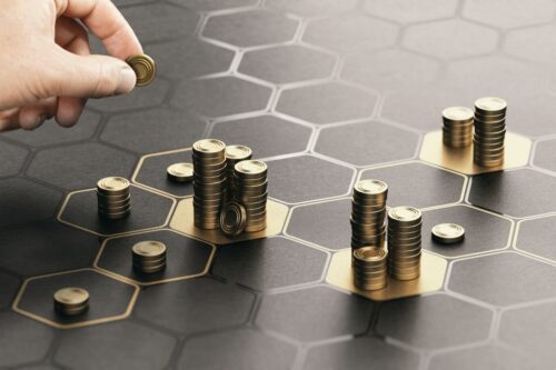 Mão empilhando moedas em hexágonos, representando a evolução do mercado financeiro e investimento em startups.