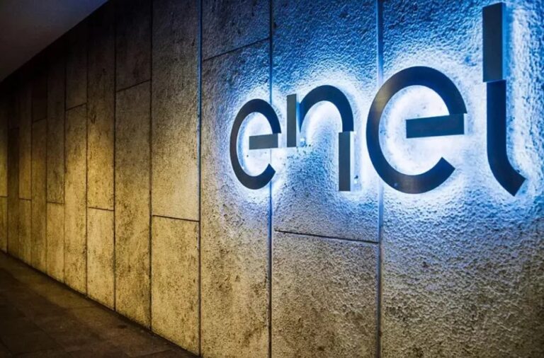 Logotipo da Enel iluminado em azul neon em uma parede interna de textura rochosa ou concreto.
