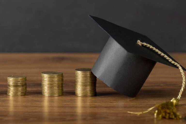 Pilhas de moedas com chapéu de formatura, representando o crescimento financeiro, ideal para empresas do setor de educação para investir.