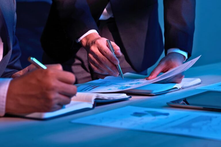 Profissionais analisando documentos financeiros em mesa de trabalho durante teste de impairment, em ambiente corporativo iluminado.