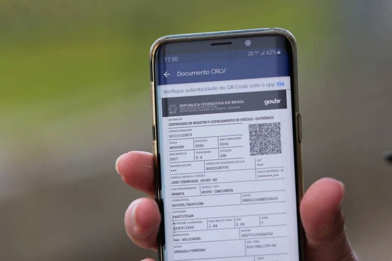 Pessoa exibindo o CRLV 2025 digital em um celular, com QR Code visível para autenticação do documento eletrônico.