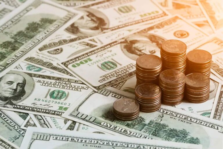 Pilhas de moedas e notas de dólar dos EUA simbolizando a alta do dólar hoje com foco nos decretos de Donald Trump.