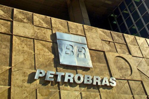 Fachada da Petrobras com logotipo em metal, representando o prejuízo da Petrobras devido a oscilações no mercado de petróleo.