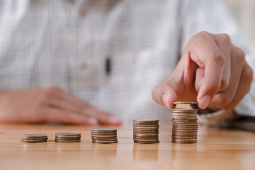 Pessoa empilhando moedas, simbolizando investimento e quanto rende 1 milhão no Tesouro Direto.