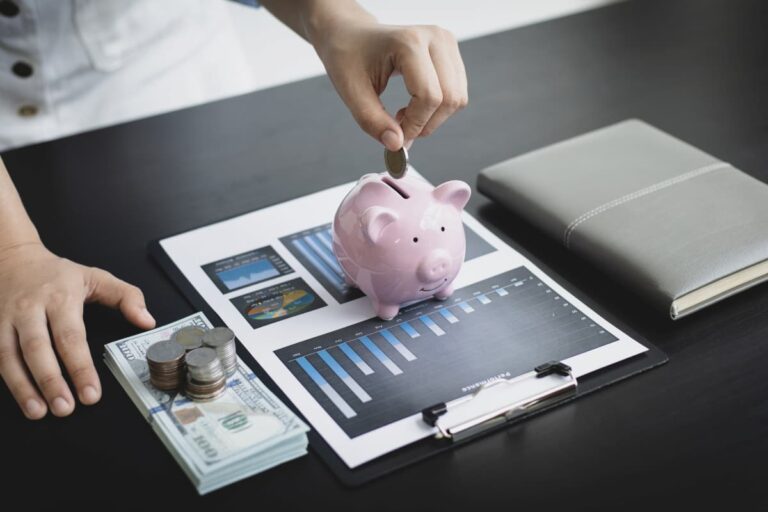 Mulher colocando dinheiro em um cofre em forma de porquinho sobre a mesa, simbolizando quanto rende 20 mil na poupança.