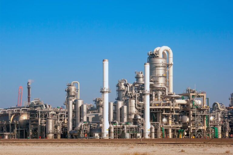 Refinaria de petróleo sob céu azul, ilustrando cenário em que o petróleo hoje cai devido a fatores econômicos e geopolíticos.