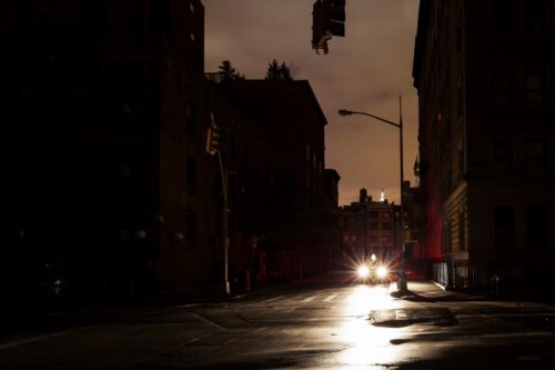 Rua escura com semáforo apagado e faróis de carro acesos, ilustrando o impacto de um apagão na Europa.