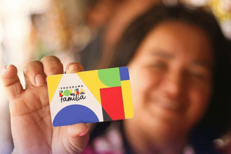 Foto de uma mulher segurando o cartão do Bolsa Família.