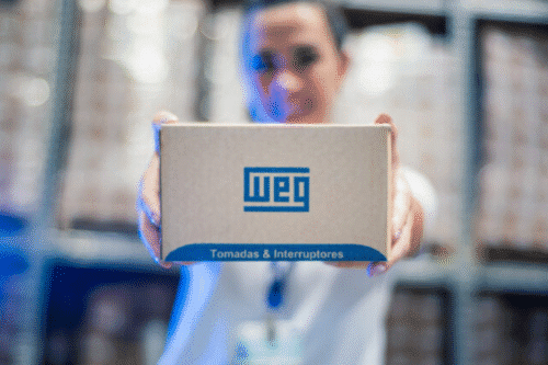 Foto de uma pessoa segurando uma caixa de papelão com o logotipo da WEG.
