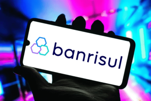 Imagem de smartphone exibindo o logo do banco Banrisul, com fundo colorido vibrante e tecnologia moderna.