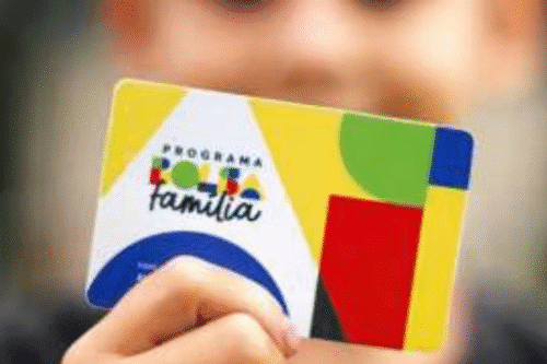 Cartão do Programa Família, destaque para cores vibrantes e o logotipo do programa social brasileiro, com fundo desfocado e uma mão segurando o cartão.