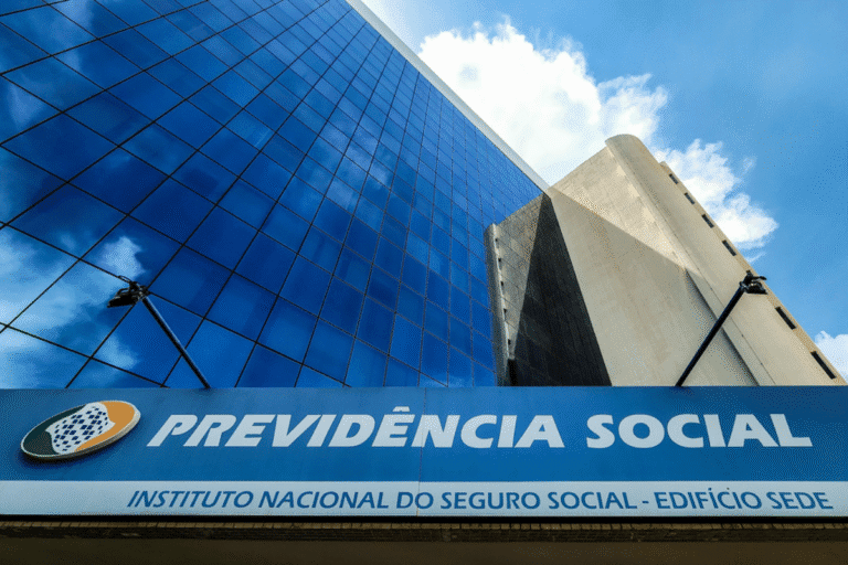Imagem do prédio da Previdência Social com fachada de vidro refletindo o céu azul e nuvens, localizado no Instituto Nacional do Seguro Social.