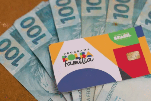 Cartão Bolsa Família em cima de notas de R$ 100 reias