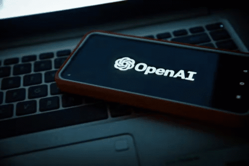 Imagem de um smartphone exibindo o logo da OpenAI, colocado sobre um teclado de laptop, representando tecnologia e inteligência artificial.