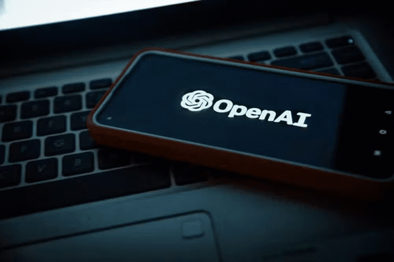 Imagem de um smartphone exibindo o logo da OpenAI, colocado sobre um teclado de laptop, representando tecnologia e inteligência artificial.