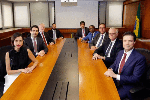 Reunião do Copom em uma sala de conferências com mesa grande, homens e mulheres de negócios em trajes formais, ambiente corporativo, bandeira brasileira ao fundo, discutindo estratégias empresariais.