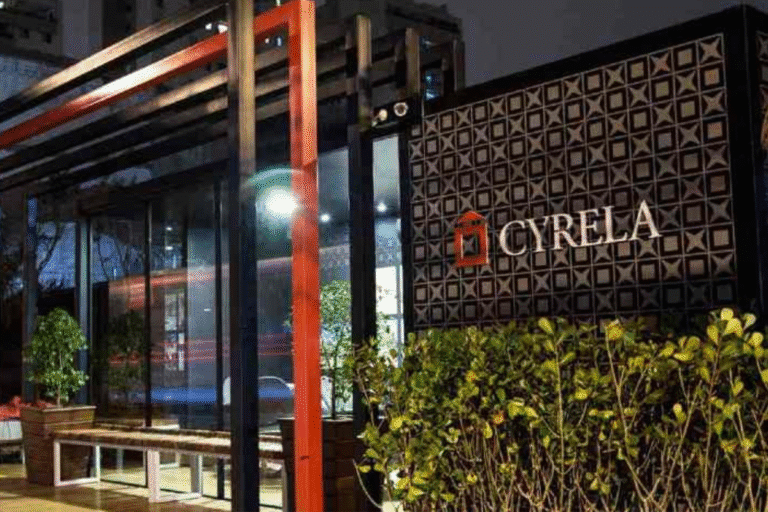 Imagem de fachada de um restaurante chamado Cyrela com design moderno e iluminação noturna, destaque para as plantas na frente e a placa com nome da marca.