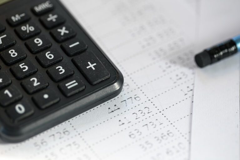Calculadora financeira e papel com balanço de contas, foco em cálculo de finanças e gestão de dinheiro, ideal para planejamento financeiro.