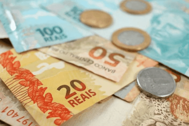 Dinheiro brasileiro com notas de 20 e 50 reais e moedas de um real, mostrando diferentes valores e detalhes das cédulas e moedas.