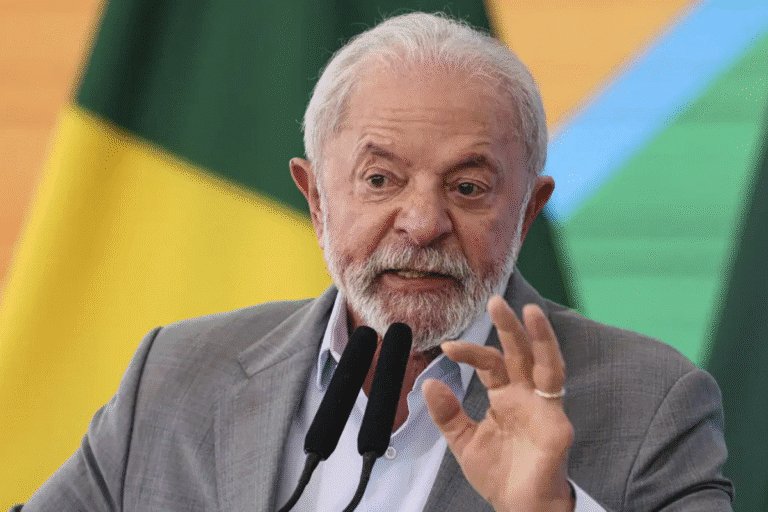 Lula durante discurso político, usando terno cinza, com fundo da bandeira do Brasil, destacando-se pela expressão facial e gestos durante fala.