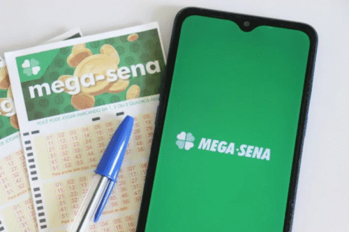 Imagem de um celular com aplicativo da Mega-Sena na tela, ao lado de apostas da loteria Mega-Sena e uma caneta, representando jogos de loteria e apostas no Brasil.
