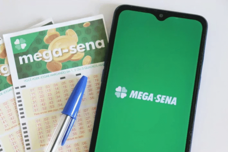 Imagem de um celular com aplicativo da Mega-Sena na tela, ao lado de apostas da loteria Mega-Sena e uma caneta, representando jogos de loteria e apostas no Brasil.
