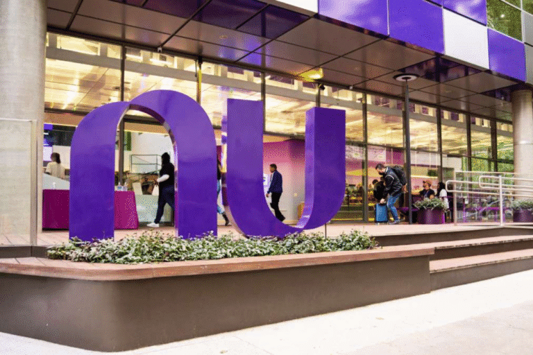 Fachada de um prédio moderno com uma grande estrutura de letras roxas formando a palavra 'OUI', com pessoas interagindo dentro do espaço. Ambiente bem iluminado e com decoração contemporânea.